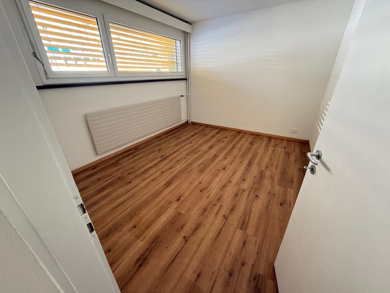 empty room, wooden floor, white walls, white radiator, large window with blinds
