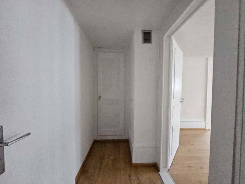 hallway with wooden floors, white walls, and two doors