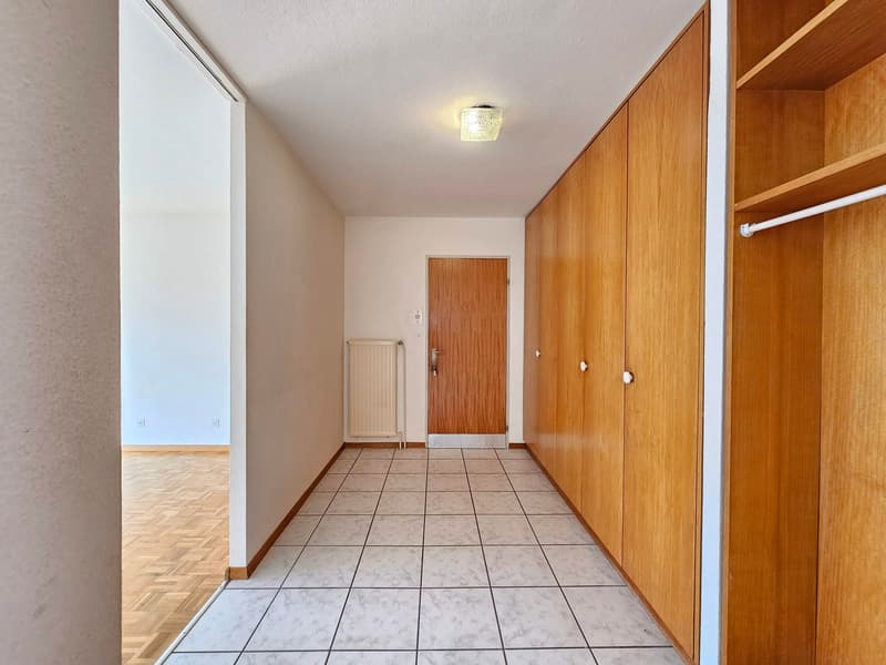 White floor, wooden cabinets, radiator, entrance door