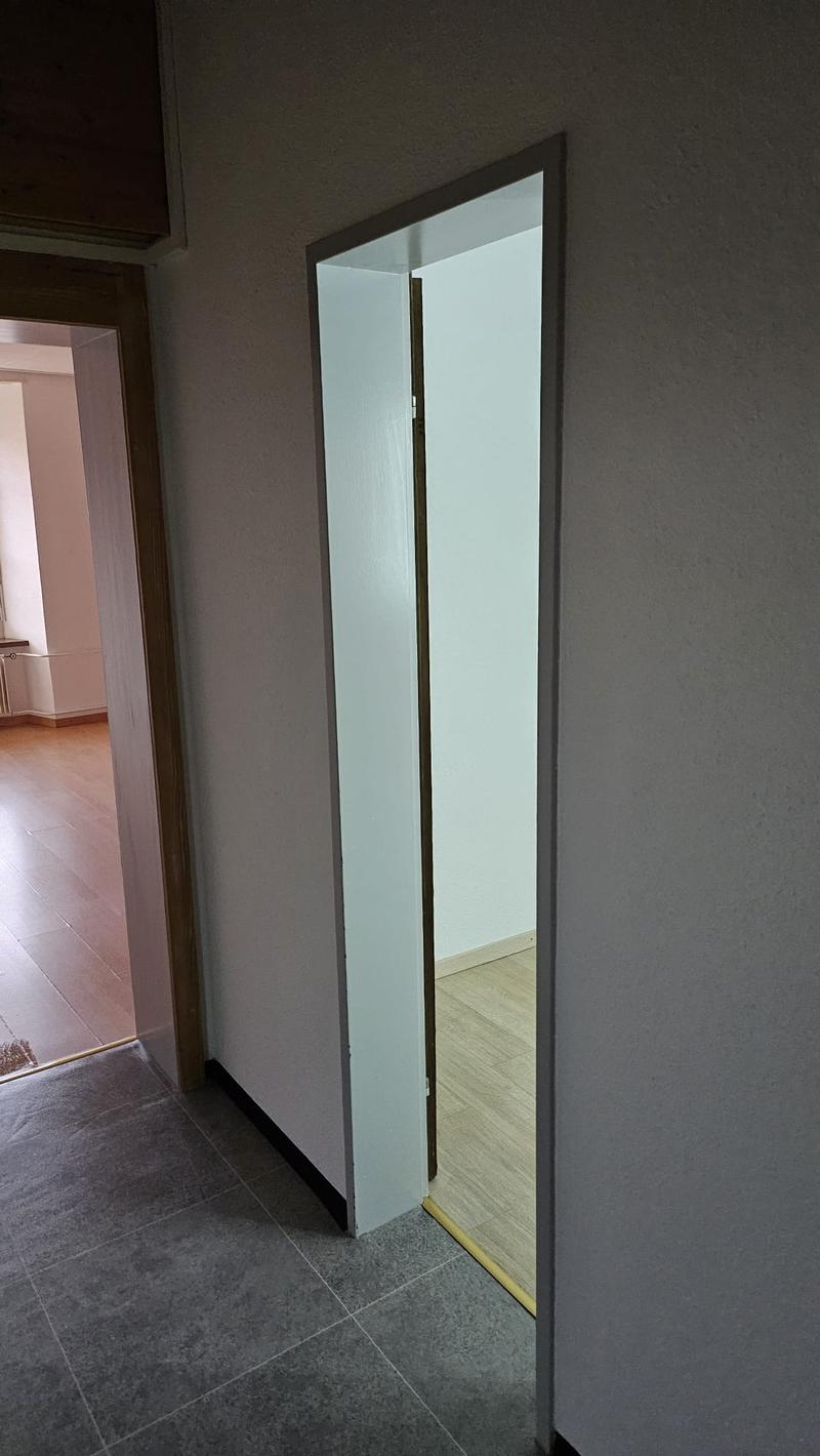 Empty room with sliding door, tile floor, wooden floor of adjacent room, visible