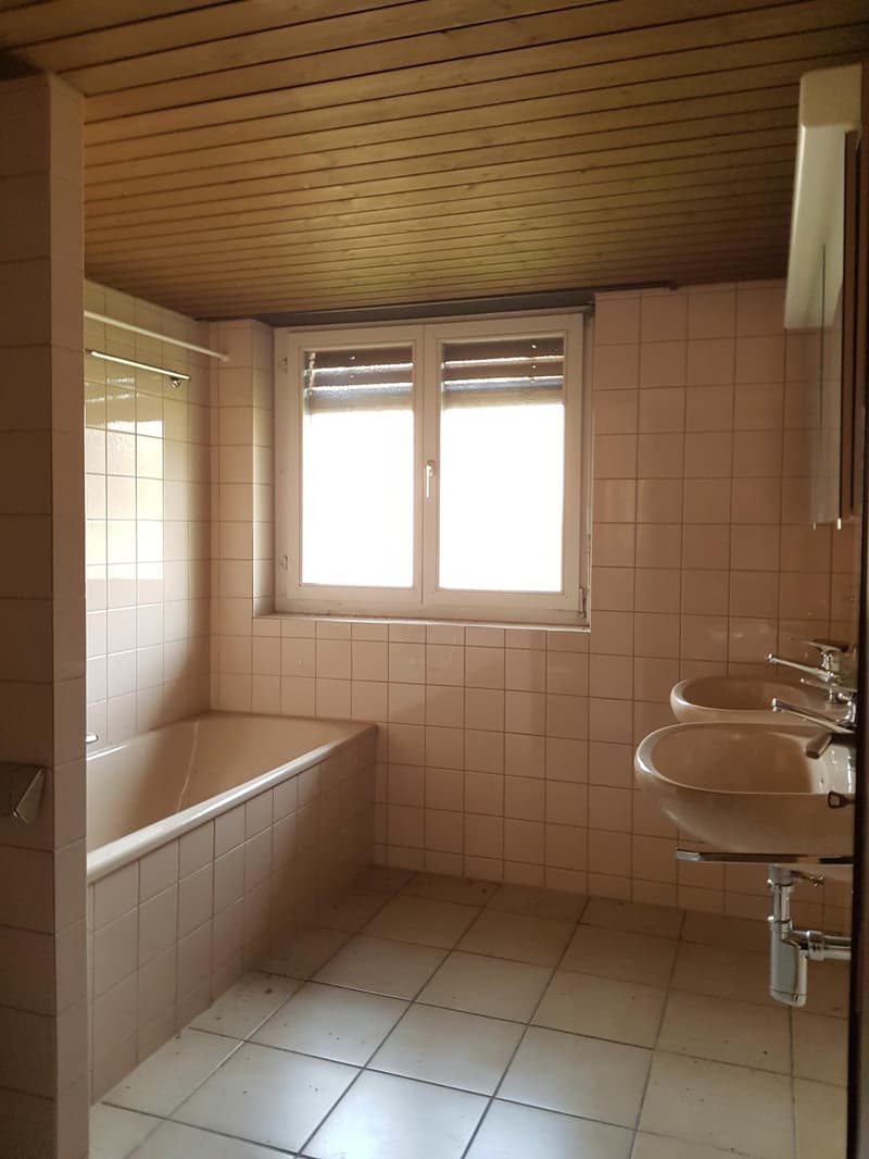 Bathroom with bathtub, two sinks, white tiles, wooden ceiling