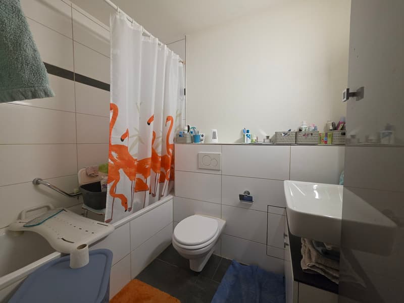 Bathroom with white tiles, white bathtub, white toilet, white sink, white shower curtain, towel, and various toiletries