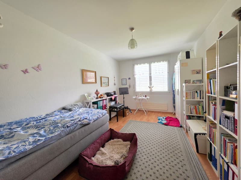 bedroom with bed, dog bed, rug, bookshelves, desk, chair, radiator, window with blinds