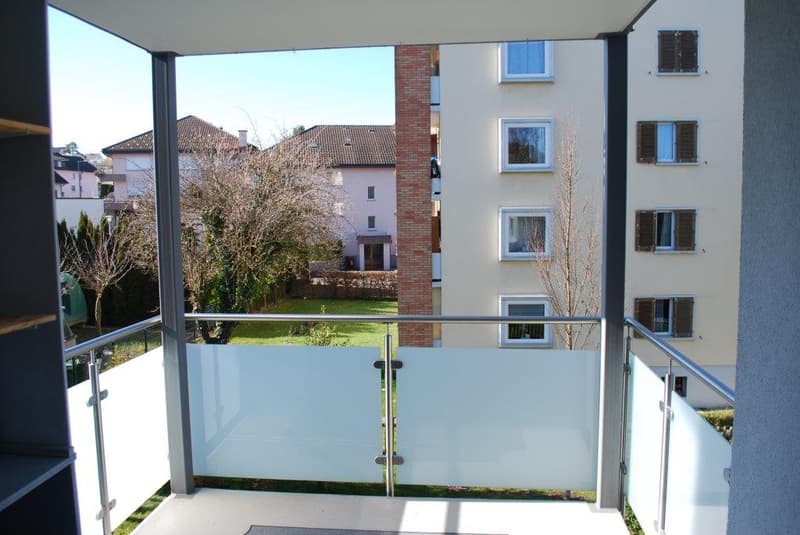 glass balcony railing, white glass panels, metal structure, overlooking the garden