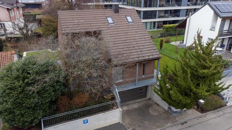 2 story house, brown roof, brick walls, garage, solar panels on neighboring house