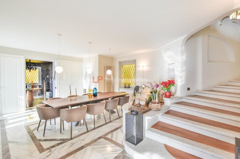 Marble flooring, wooden table, wooden chairs, pendant lights, staircase, floral decor