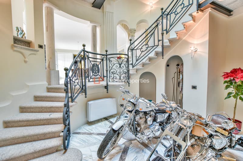 Main entrance with marble floors, grand staircase, marble and metal handrails, a heater mounted on the wall, three vintage motorcycles