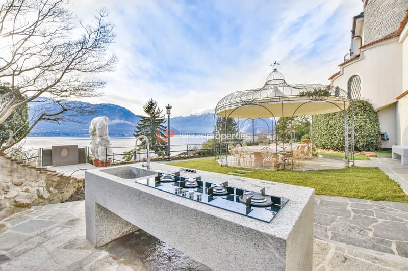 Outdoor kitchen, dining area under a gazebo, a statue, a fountain, view of the mountains and the lake