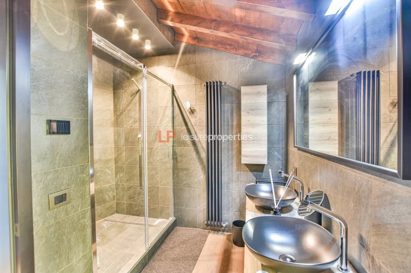 Modern bathroom with shower, double sink, wooden ceiling, tiled walls, floor heating