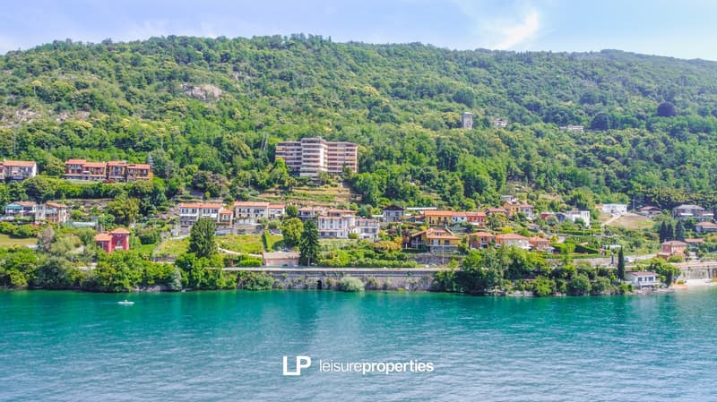 hillside community with multiple houses overlooking a river, trees and greenery, houses are in various colors