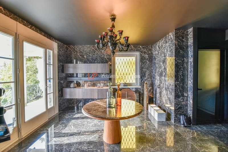Modern interior, wooden table, glass and marble flooring, large chandelier, large doors