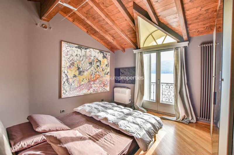 double bed, 3 pillows, wall painting, wooden ceiling, wooden floor, balcony doors, balcony view