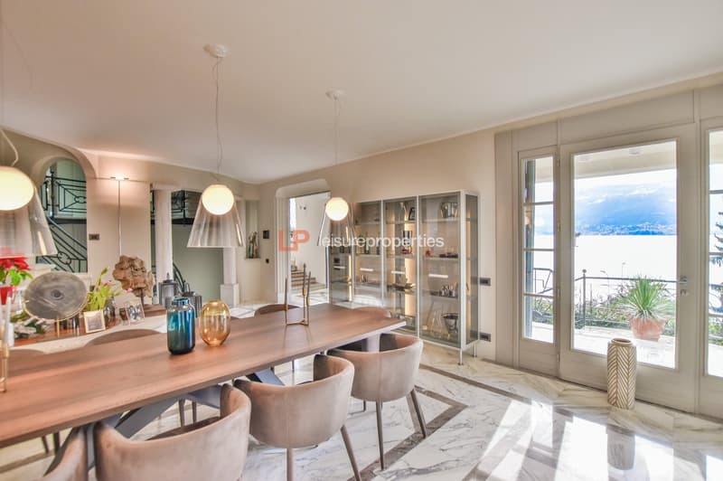 wooden table, chairs, decorative vases, modern design, white marble floor, large windows, balcony, view of lake and mountains