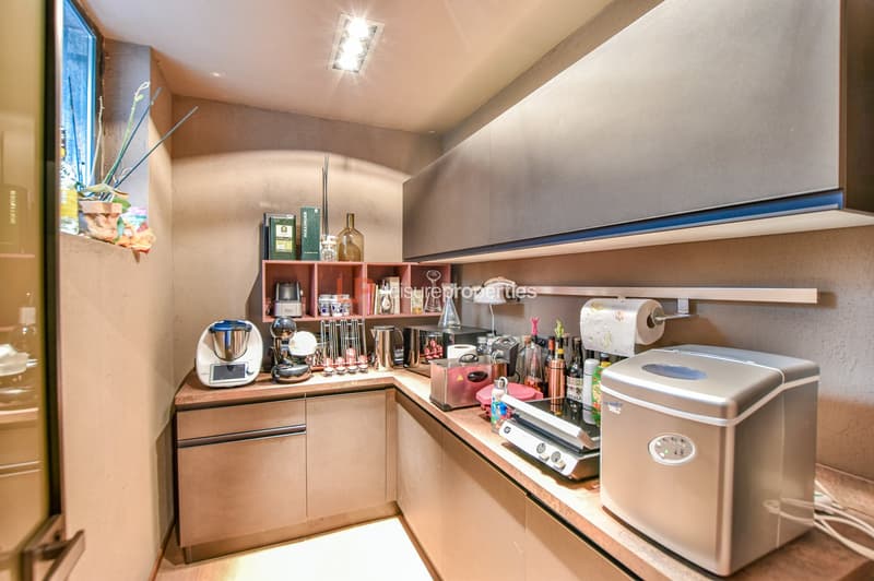 small kitchen area with built-in appliances and countertop, modern decor, warm lighting