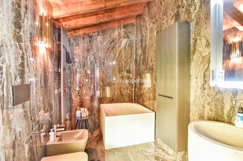 marble floor and walls, bathtub, sinks, toilet, mirror, wooden ceiling