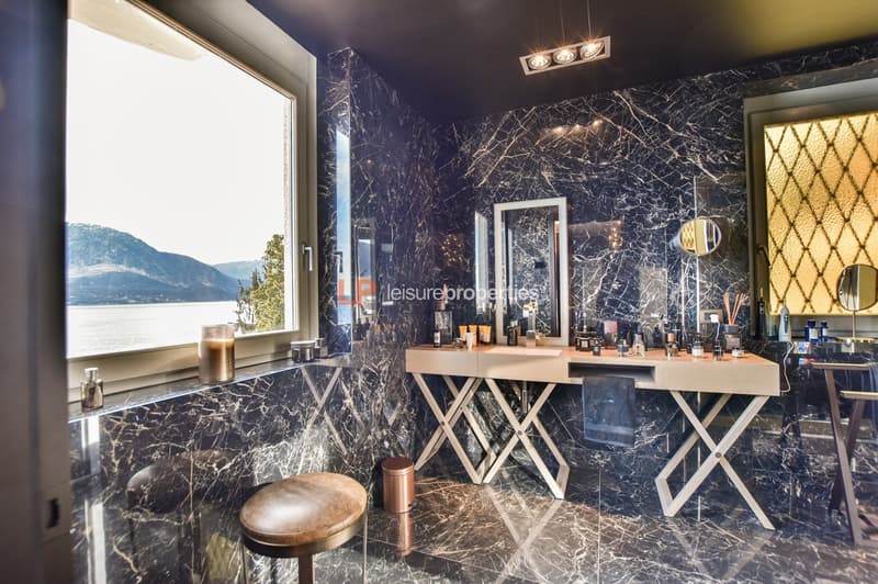 marble walls, window, two sinks, stool, trash bin, mirrors, toiletries, mountains view
