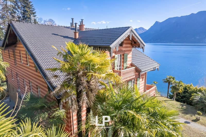 two-story wooden house, brick walls, large roof, several windows, wooden balcony, overlooking a large lake