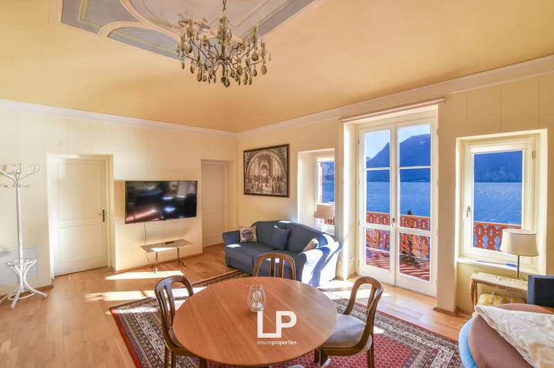 open space with living room area and dining table, balcony, glass doors, ocean view, chandelier, blue sofa, TV, carpet, floor lamp