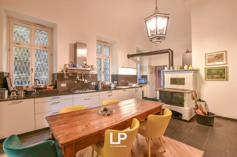 kitchen with gas stove, oven, kitchen island, dining table, wooden floor, white cabinets, tiled flooring, fireplace