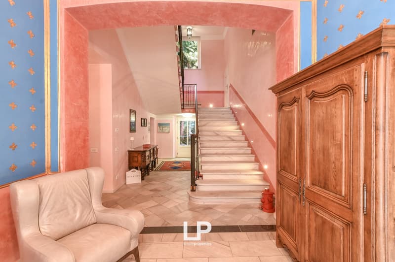 Staircase, pink walls, white tiled floor, wooden cabinet, blue and gold painted wall, armchair