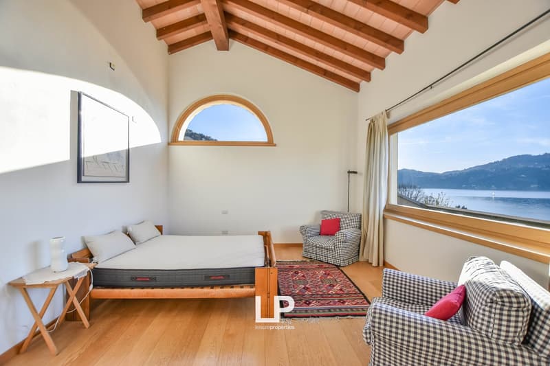 large windows, wooden flooring, arched window, sea view, wooden bed, armchair, rug