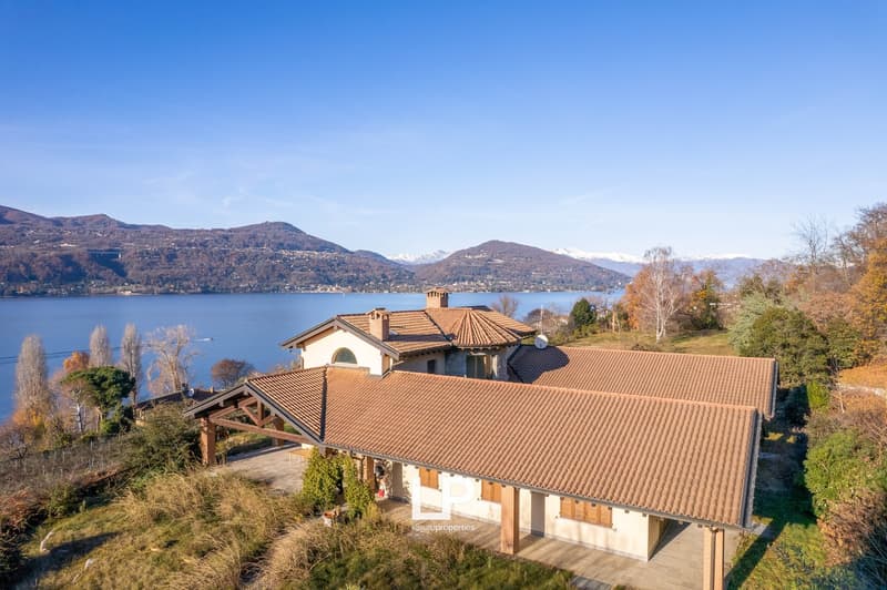 2-story house with terracotta tile roof, surrounded by trees and overlooking a lake and mountains in the distance