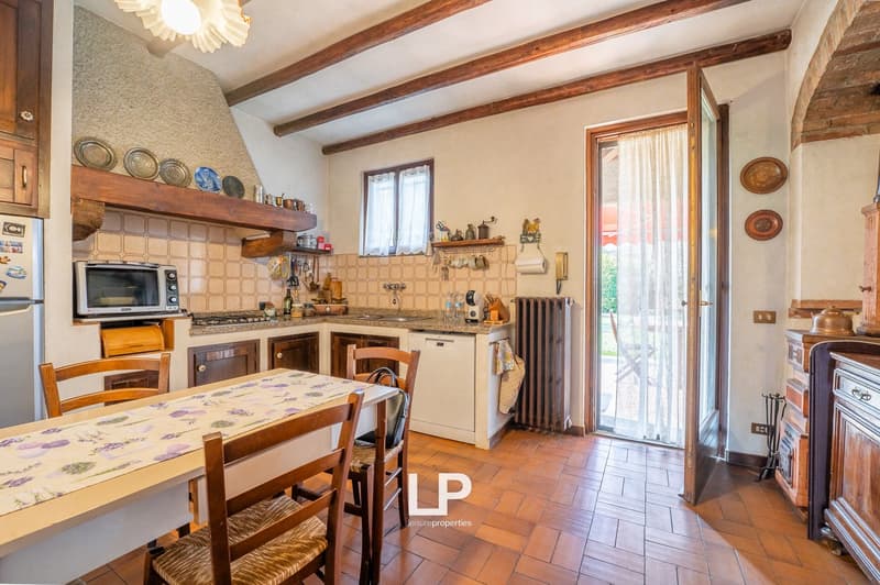 wooden beams, fireplace, wooden floor, dining table, chairs, microwave, dishwasher, refrigerator, wooden cabinets, tiled walls, open door