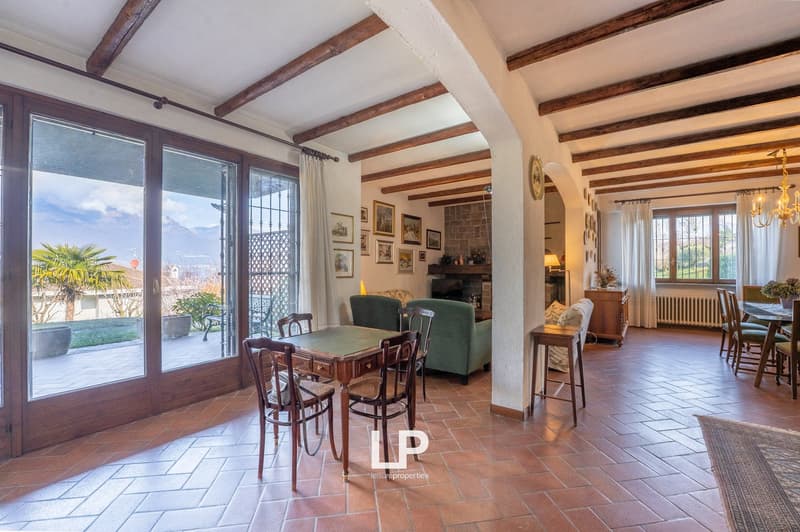 dining room with wooden table, chairs, fireplace, large windows, balcony, wooden beams, tiled floor