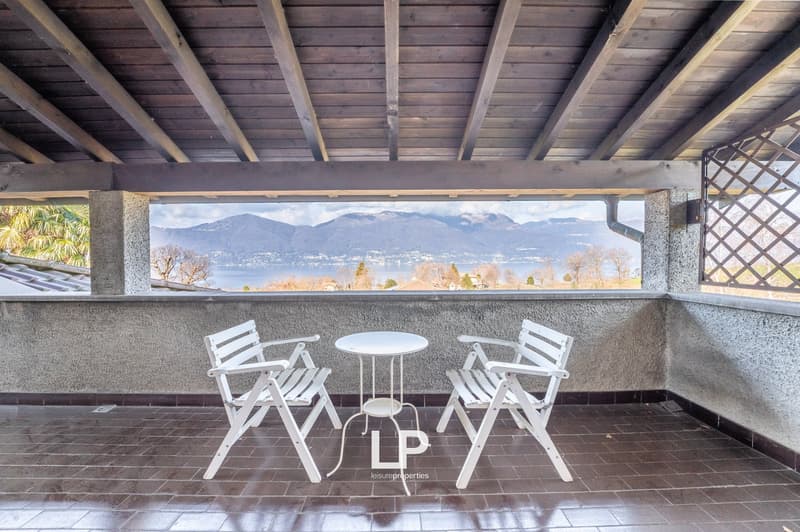 covered terrace, white chairs, small table, tiled floor, view of mountains and lake