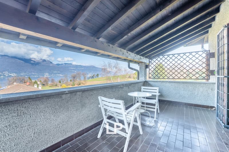 balcony with table and chairs, tiled floor, view of mountains and lake