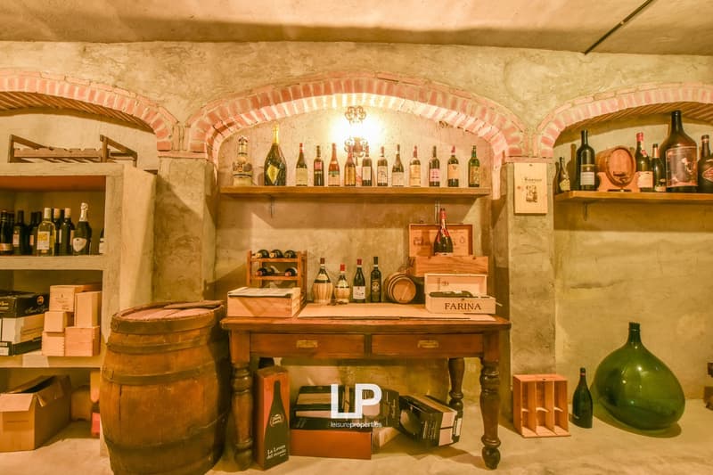 basement wine cellar, wooden table, wine racks, wine bottles, wooden barrels