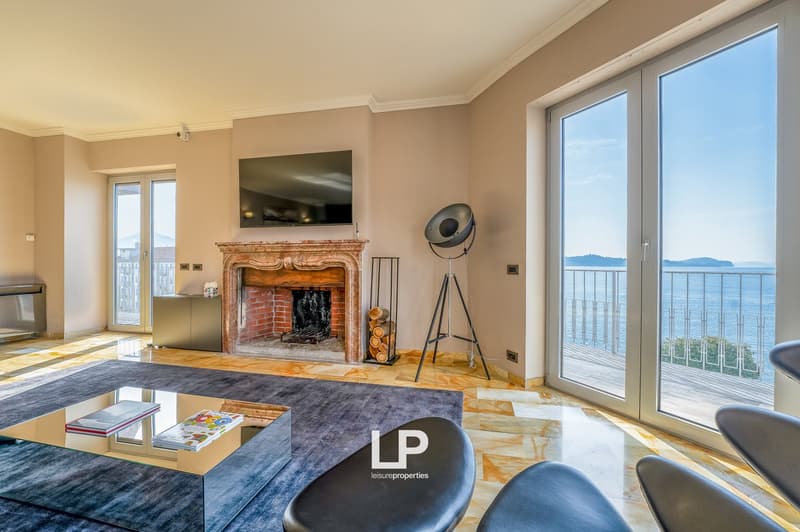 Spacious living room with large windows offering a scenic view, a brick fireplace, hardwood floors, and modern furniture including a coffee table and chairs.