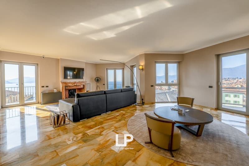 Spacious living room with large windows offering a scenic view, hardwood flooring, a fireplace, a sofa, and a round dining table with chairs.