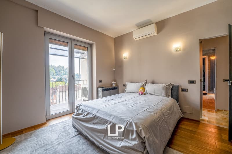 Spacious bedroom with large windows, hardwood floor, gray bedding, air conditioning unit, and access to a balcony or terrace