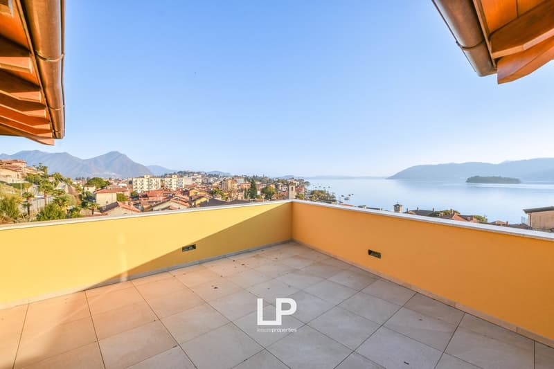Large balcony with yellow wall, view of the sea, mountains, and city.