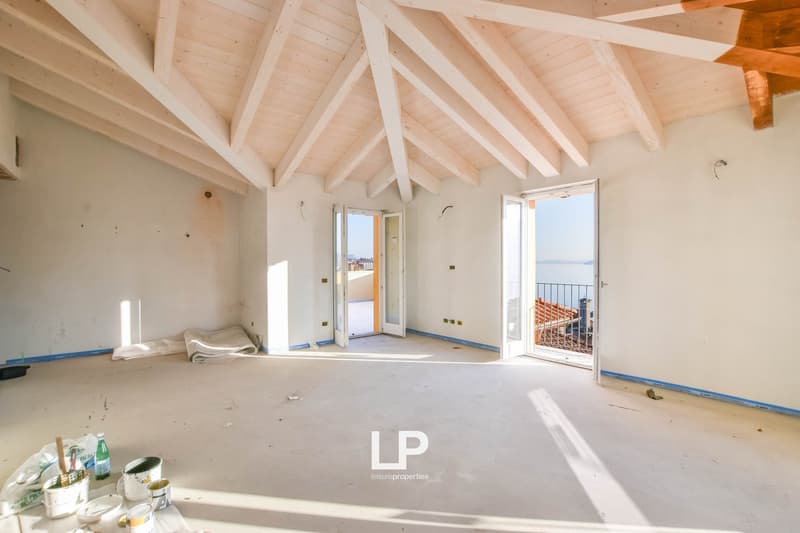 Empty room, white walls, wooden ceiling, blue trim, open doors, balcony, view