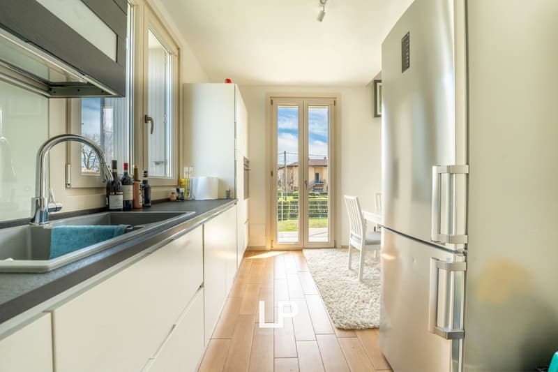 modern kitchen, white cabinets, stainless steel sink, faucet, refrigerator, floor-to-ceiling windows, wooden floor, view of garden and balcony