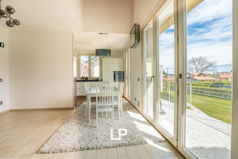 Contemporary dining area with white modern furniture, large windows, sliding glass doors to a balcony