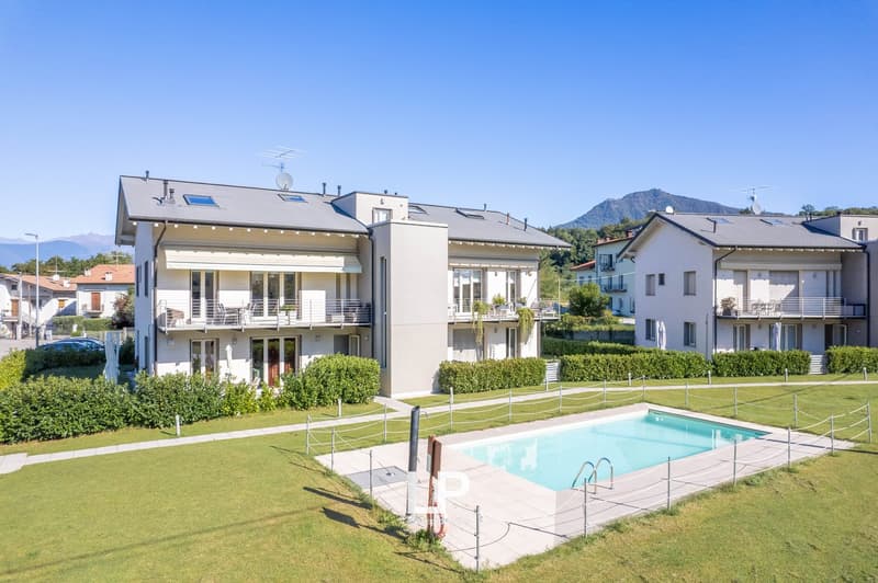 Multi-story apartment buildings with balconies, surrounded by landscaped gardens and a swimming pool.