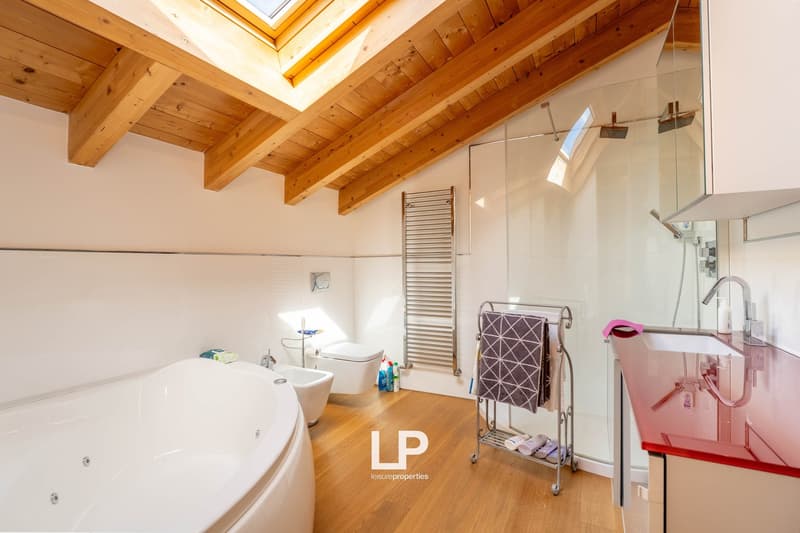 white bathtub, large shower, white toilet, towel rack, wooden floors, skylight, red countertop, towel rack