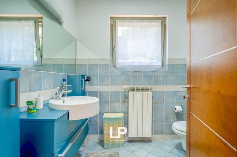 Tiled bathroom with blue vanity, round sink, radiator, and window