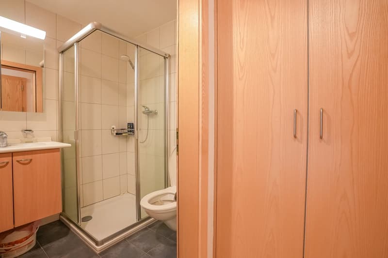 Bathroom with a glass shower enclosure, tile floor, vanity with sink, and wooden cabinets.