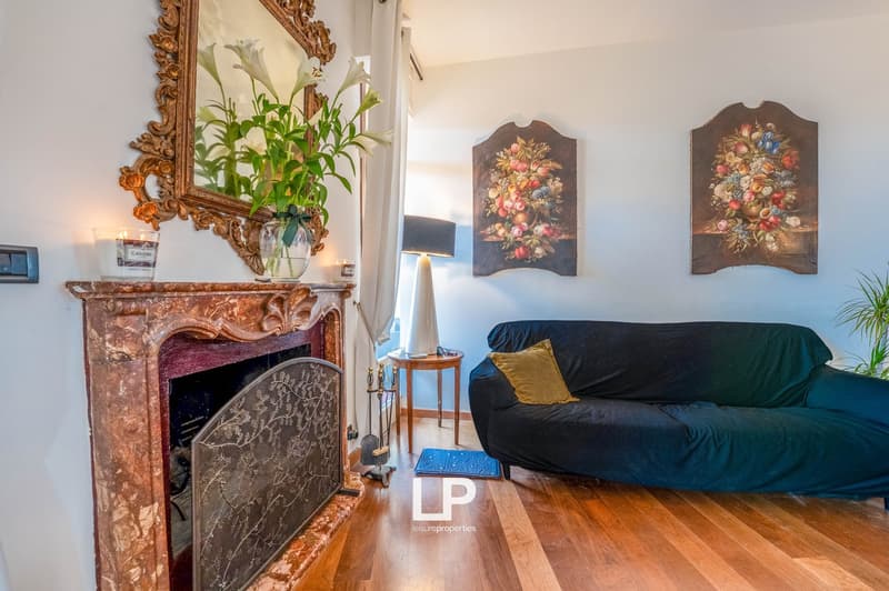Ornate gold-framed mirror, floral arrangements, antique-style paintings, dark blue sofa, wooden floor