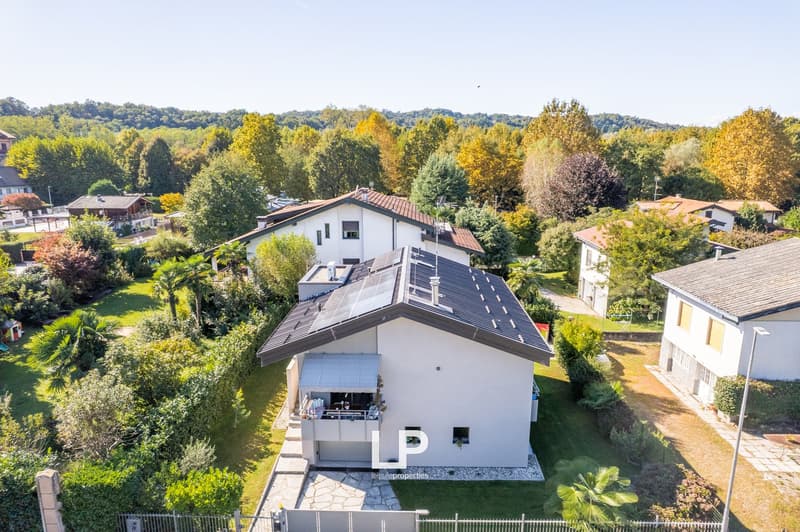 Detached house, solar panels, white exterior, brown roof, garage, large balcony, multiple windows, located in a suburban setting