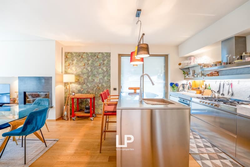 Open concept kitchen with modern appliances, including a dishwasher, and a dining area with a table and chairs. The kitchen has a mix of wood and tile elements, and the living room is visible in the background.