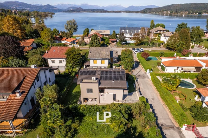 modern houses in a small town, surrounded by greenery, lake in the background, solar panels on one house