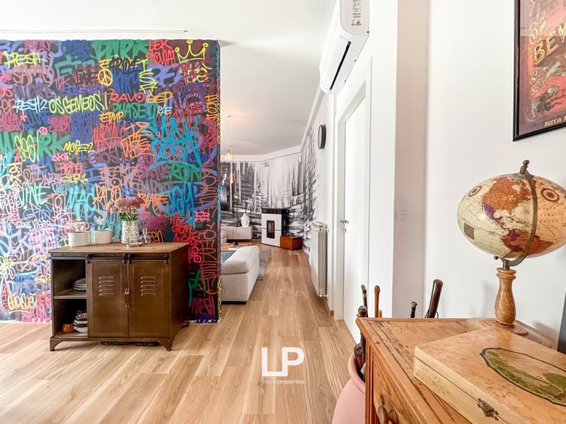 Colorful graffiti-style wall, wooden floor, vintage cabinet, globe, artwork on the wall