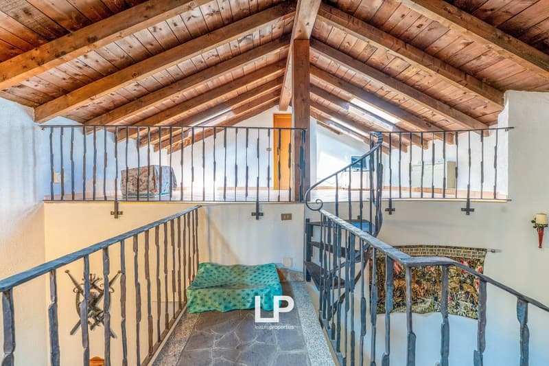 Wooden beamed ceiling, balcony with metal railing, stone floor, couch
