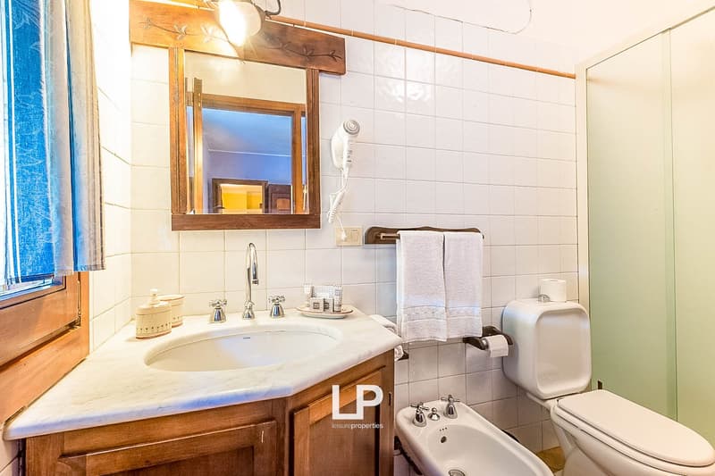Bathroom with white tile walls, wooden vanity with sink, mirror, towel rack, and a private washing machine
