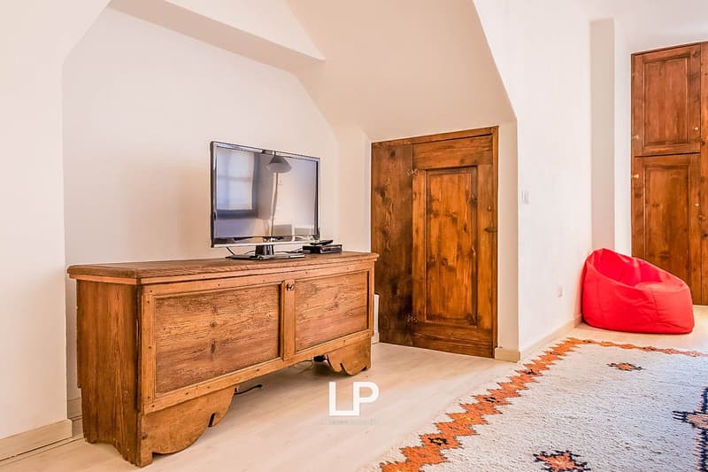 Wooden TV stand, wooden doors, red bean bag chair, patterned rug